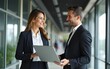 © shu - Happy busy professional smiling businessman and businesswoman having conversation at work. Executives team of two business people working talking using laptop technology standing in corporate office.