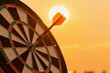 © Worldwide - Dartboard silhouetted against a sunset with a dart in flight.