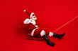 © deagreez - Santa Claus enjoying the holiday spirit on a sled with a festive gift bag against a vibrant red background