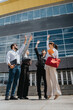 © qunica.com - A team stands together outside a modern office building, actively celebrating a mutual achievement.