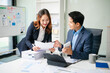 © laddawan - Asian businessman and woman workers talking on the smartphone and using laptop Professionals in Teamwork Finance, Marketing
