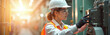 © miss irine - Woman engineer inspects machine panel in bright factory. Safety gear includes hard hat and glasses. Professional works with industrial equipment on production line.