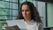 © Yuliia - Sad Hispanic business woman opening letter bad news open paper envelope reading reject bank deny Arabian ethnic businesswoman female girl read stressed information work faired unemployment upset lady