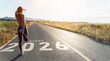 © Yingyaipumi - New year 2026 or start straight concept.word 2026 written on the asphalt road and athlete woman runner stretching leg preparing for new year at sunset.Concept of challenge or career path and change.
