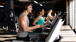 © Home-stock - Sporty smiling man running on treadmill in gym, wearing headphones, enjoying morning workout with music, side view, panorama