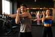 © Home-stock - Strong man and woman stretching, warming up in fitness studio, both wearing sportwear and smiling