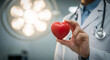© Eshana - Doctor holding a red heart in his hand wearing a white coat and a stethoscope in a hospital room