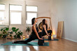 © phoenix021 - Two women practicing yoga together, one on one class, gong and plants in the back