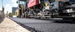 © Fernando - Asphalt paver machine laying new asphalt on road construction site on a sunny day Concept of infrastructure, roadwork, and civil engineering