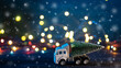 © pavelkant - A toy truck transports a Christmas tree. Blue bokeh background with garland and falling snow.