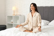 © Pixel-Shot - Young beautiful woman meditating on bed