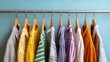 © soem - A colorful collection of clothing hanging on a metal rack against a light blue wall.