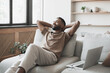 © kite_rin - Satisfied handsome young man relaxing on sofa at home in living room, resting after a hard day work, closed eyes, put hands behind head, smiles happily. Relaxation, day off, enjoy life and holiday