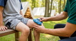 © Tapasii - A parent applies an Ice pack on child's knee at a campsite, a photo for articles about outdoor safety and family first aid.