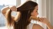 © Vasiliy - Woman combing her long healthy brown hair with a wooden comb. Natural hair care and daily beauty routine concept