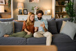 © Westend61 - Couple sitting on couch using digital tablet and smiling at home
