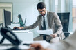 © Westend61 - Businessman in suit reading document at desk in modern office
