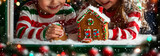 children in striped christmas pajamas making a gingerbread house near a window	
