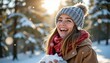© Chaithat - Young woman laughing joyfully while holding snow outdoors in a sunny winter forest scene