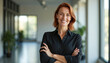 © Pete - Brunette woman stands confidently in bright office space smiling warmly. Wears black suit, arms crossed. Image conveys professionalism success, positive energy within modern corporate environment.