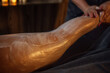 © Dasha Petrenko - Female therapist applying soothing body treatment on a client's leg, showcasing a relaxing spa environment with soft lighting and calming ambiance for wellness and rejuvenation