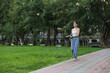 © leungchopan - Woman carrying yoga mat walking in park outdoors