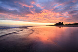 Dramatic sunrise above beach at Bamburgh Castle on The Northumberland Coast, UK.