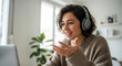 © Olga Ко - Jeune femme freelance française, portant un casque audio et racontant quelque chose avec enthousiasme pendant une visioconférence. Ambiance de travail à domicile, création de contenu, cours en ligne.