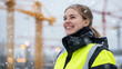 © photo for everything - Cheerful construction worker enjoying snowfall at the construction site, clad in high-vis gear, she looks up at the sky and smiles. Cranes in the backdrop.