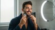 © O - A happy man in a bathroom mirror trimming his beard with an electric razor. Male grooming and morning routine concept.