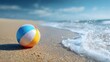© Aoun - Colorful wet beach ball resting on sandy shore near ocean waves under bright summer sunlight