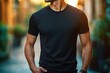 © Margarita - Confident man with trimmed beard wearing a fitted black t-shirt and wristband, standing with hands in pockets on a sunlit blurred street in a relaxed casual pose