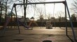 © WELAS - A teddy bear sits alone on a swing set in a playground at sunset