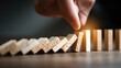 © koranis - A hand pushes the domino effect, stopping the fall of dominoes, symbolizing prevention and control.