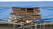 © Repa - Damaged roof covered with blue tarp showing exposed rafters and icicles hanging