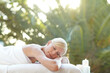 © Reese Coop/peopleimages.com - Woman, rest and nap at spa outdoor for sunlight therapy, fresh air and pamper session. Female person, sleeping and lens flare for holistic wellness, natural healing and bokeh for self care at retreat