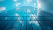 © Arslan - Low angle view of a glass skyscraper reflecting the clouds and blue sky on a bright sunny day