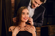 © Prostock-studio - Handsome man wearing necklace on his attractive young woman. Happy Saint Valentine's Day concept