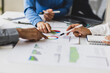 © Wasan - Business people analyzing financial charts and graphs at meeting.