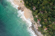 © Mint Images - Aerial View of Casitas Marika beach, small beach huts and a thick cover of palm trees and forest.