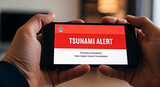 A person reading a tsunami alert on their phone for the concept of natural disaster and alert.