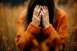 © Margarita Ratatosk - Woman in orange sweater covering face with hands. Depressed or upset concept of sadness and anxiety in autumn season for mental health awareness.