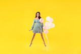 Beautiful woman with balloons jumping on orange background