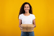 © Prostock-studio - Cheerful young lady stands in a studio holding a stack of pizza boxes. She smiles at the camera, with a bright yellow background creating a joyful atmosphere, perfect for a fast food delivery theme.