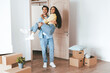 © Prostock-studio - A couple is having fun moving into their new home. The man playfully lifts the woman while surrounded by unpacked boxes and bright sunlight. Happiness fills the room.