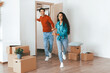 © Prostock-studio - A cheerful couple excitedly runs into their new home carrying joy and anticipation. The empty room is decorated with moving boxes, showing the beginning of their new life.