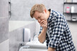 © New Africa - Young man suffering from nausea over sink in bathroom