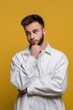© Andrii Zastrozhnov - Thoughtful young caucasian male in white shirt pondering on yellow background