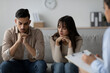 © Prostock-studio - Arab husband and wife sit at a therapy session, appearing distressed and thoughtful. They listen as their psychologist offers advice to help resolve their relationship difficulties.