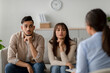 © Prostock-studio - In a therapy session, Arab spouses express their emotions as they listen to advice from a professional counselor. They sit together on a couch, reflecting on their relationship issues.